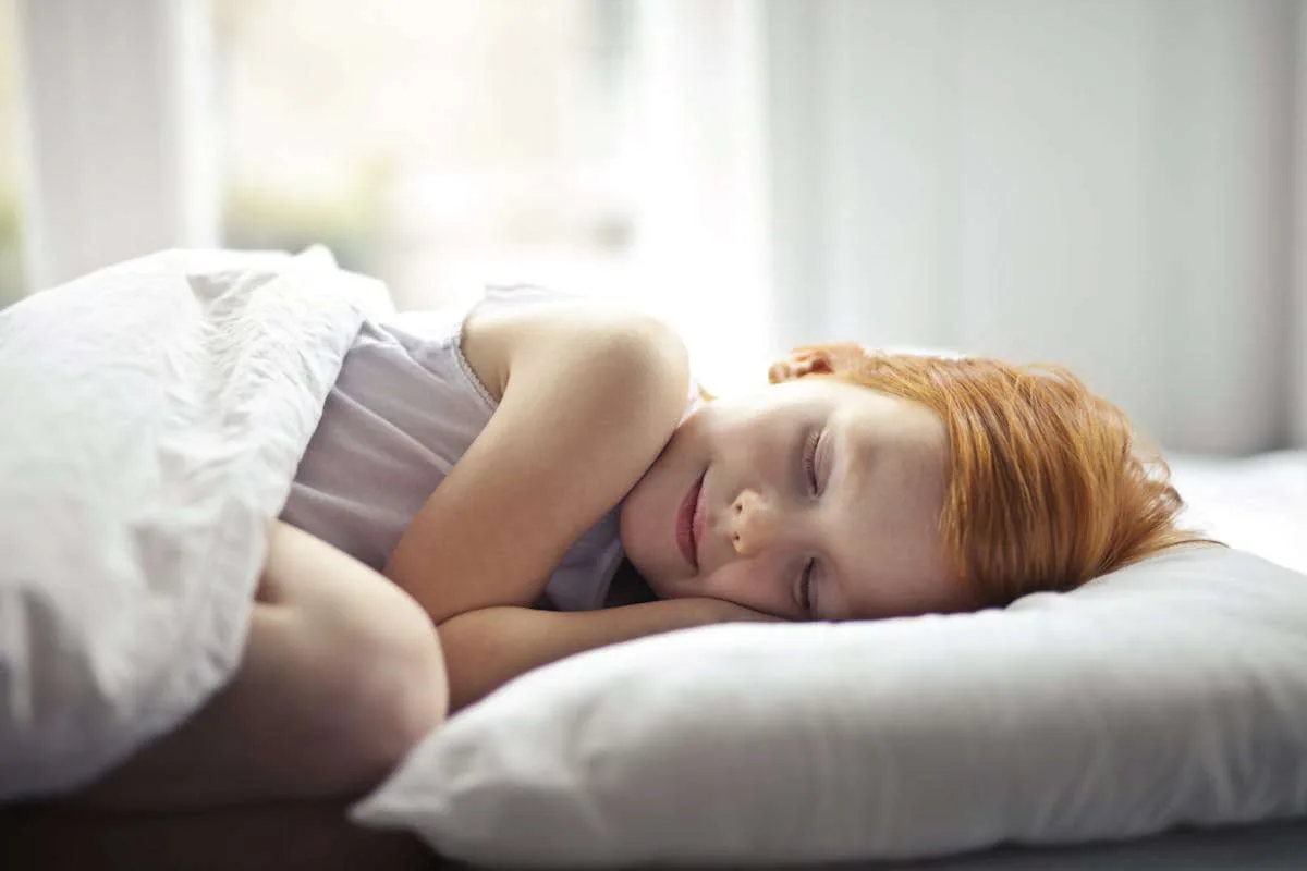 Little girl sleeping peacefully on her bed. Their sleep can be affected by caffeine.