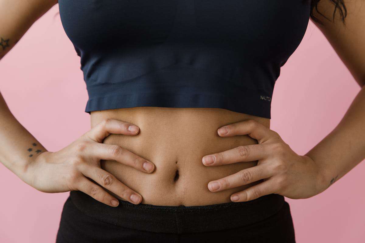 A picture of a woman holding her waist and belly as a sign of healthy gut.