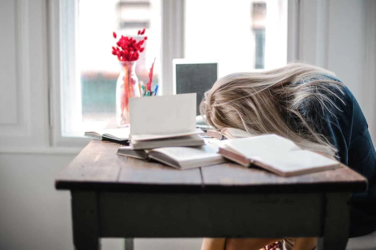 A sick woman put her head down on the table portraying her hormonal imbalanced state.