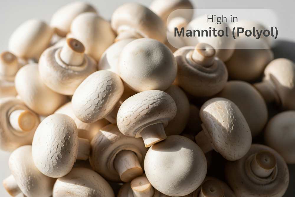 A natural light shot of a pile of fresh white button mushrooms with text overlay: “High in Mannitol (Polyol).”